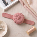 Dusty Rose Corduroy Pin Cushion on a textured surface with fabric and a spool of thread.