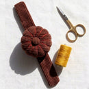 Spiced Cocoa Corduroy Pin Cushion with scissors and yellow thread on a white background