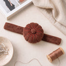 Spiced Cocoa Corduroy Pin Cushion on a light surface with a spool of thread.