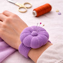 Purple corded pin cushion on a wrist with sewing tools in the background
